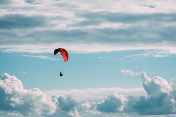 Red parachute in cloudy sky